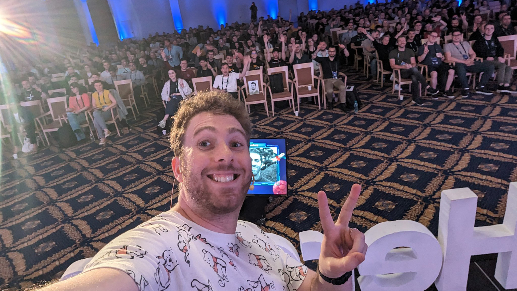 Smiling selfie of me giving the peace symbol on stage at JSHeroes.